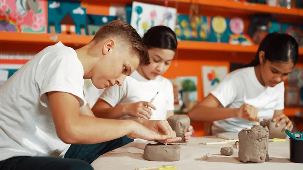 Group of happy smart diverse student working with clay art at pottery workshop. Multicultural attractive highschool student modeling, smash, playing clay. Creativity activity concept. Edification.