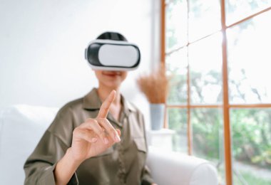 Sanal gerçeklik gözlüğü kullanan genç bir kadın online alışveriş deneyimi için evde. Sanal gerçeklik VR yeniliği dijital eğlence yaşam tarzı için optimize edildi.