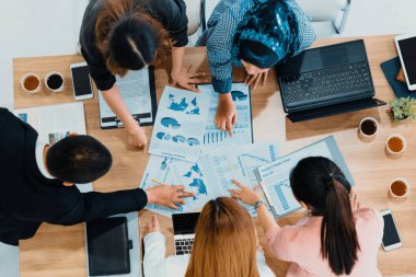 Modern ofisteki iş adamları ve iş kadınlarıyla grup toplantısındaki iş adamlarının en üst düzey görüşü, masada dizüstü bilgisayar, kahve ve belge ile. Kurumsal şirketler uds