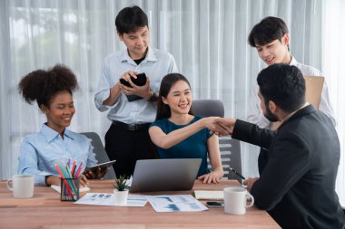 Çeşitli iş arkadaşları başarıyı şirket işyerindeki el sıkışma ve takım çalışmasıyla kutluyor. Çok kültürlü, mutlu profesyonellerden oluşan bir ekip ofiste tokalaşarak birlik oldular. Uyum