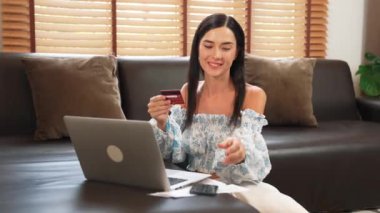 Genç bir kadın internet bankacılığı için kredi kartıyla dizüstü bilgisayar kullanıyor. Evinde online ödeme kapısı ile E ticareti yapıyor. Banka kartıyla modern ve kullanışlı online satın alma. Blithe