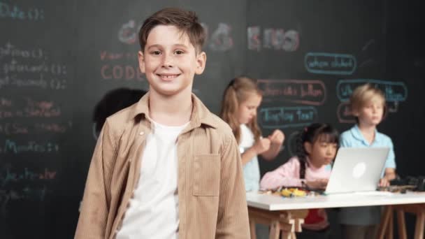 Smart Pojke Ler Mot Kameran Medan Olika Vänner Arbetar Eller — Stockvideo