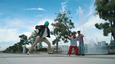 Profesyonel çekici hipster, Fountain ile sokak dansı yapıyor. Yakışıklı bir adamın B-boy ayak egzersizi sahnesi. Mavi arka plan. Modern yaşam tarzı. Açık hava sporu 2024. Yumuşak bir şekilde..
