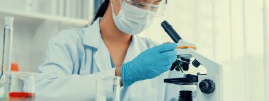 Laboratuvar araştırmacısı mikroskop kullanarak yeni ilaç ya da tedavi geliştirir. Laboratuvar mikrobiyoloji ekipmanları ile bilimsel uzmanlık ile sağlık hizmetlerinin teknolojik gelişimi. Panorama Katı