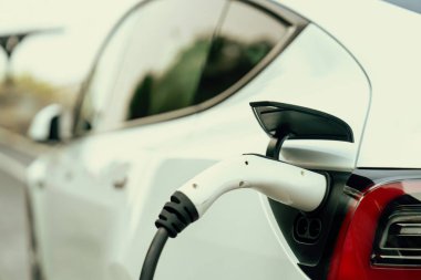 Kapalı EV şarj kolu fişe takıldı veya elektrikli arabaya bağlandı, EV araba aküsünü temiz çevre için sıfır CO2 emisyonu ile alternatif ve sürdürülebilir enerjiyle şarj etti. Kalıcı