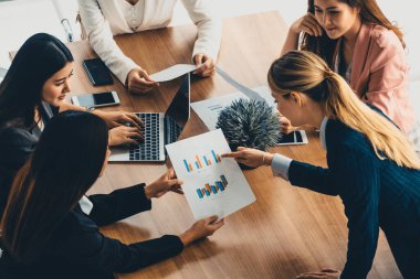 Modern işyeri ofisindeki diğer iş kadınlarıyla grup toplantısındaki iş kadını masada dizüstü bilgisayar ve belgelerle konuşuyor. Kurumsal iş dünyası konsepti. uds