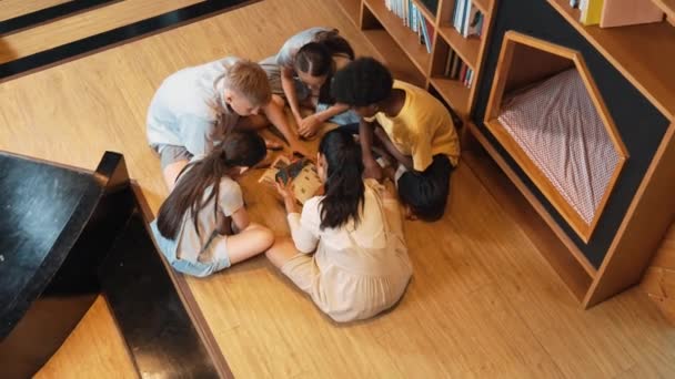 一群各种各样的孩子围坐在一起 在图书馆看书 女孩在与不同文化的朋友交流的同时 在杂志上分享自己感兴趣的话题的头像 — 图库视频影像