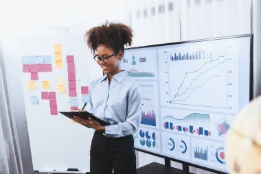 Genç Afrikalı iş kadını modern toplantıda TV ekranında veri analizi paneli sunuyor. Bir grup iş adamıyla konferans odasında iş sunumu. Uyum