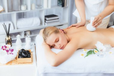 Sıcak bitkisel top spa masaj vücut tedavisi, masör kadın vücuduna nazikçe şifalı bitki torbası bastırıyor. Aromaterapi dinlenme sükuneti ve sükuneti kaplıca salonundaki atmosferi aydınlatıyor. Sessiz.