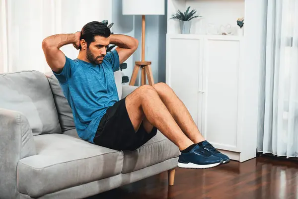 Athletic body and active sporty man using furniture for effective targeting muscle gain exercise at gaiety home exercise as concept of healthy fit body home workout lifestyle.