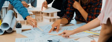 Profesyonel iç mimar analizi ve ev yapısıyla ilgili beyin fırtınası yaparken, usta mimar mühendis ekibi toplantısı planlara işaret ediyor. Yaratıcı tasarım ve takım çalışması konsepti. Filizlenen.