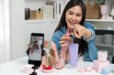 Genç, güzel Asyalı kozmetik makyaj ruju matte pastel rengini modern odadaki sosyal medyada kol testi tanıtımında en çok satanlar listesinde gösteriyor. Taktik.