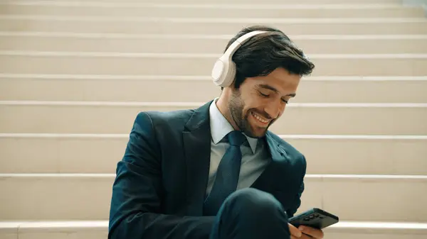 Closeup of smart business man listening and enjoy music while wear headphone. Project manager smiling while getting good news, getting promotion, increasing sales. Relaxing man enjoy music. Exultant.