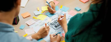 Profesyonel başlangıç grubu zihin haritası kullanarak yaratıcı pazarlama fikrini paylaşıyor. Genç yetenekli iş adamları yapışkan notlar yazarken beyin fırtınası planı yapıyorlar. Eline odaklan. - Yakın çekim. Değiştirilmiş.