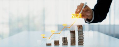 Dijital grafik göstergeli bozuk para yığını iş yatırımını ve ekonomik büyümeyi sembolize ediyor. Finansal hedefe ulaşmak ve kâr sağlamak için finansal planlama yapan bir iş adamı. Kurnaz.