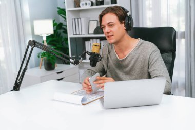 Sunucu kanalı, gülümseyen akıllı yayıncı kaydı, senaryosu ve akıllı telefonuyla sosyal medyada sohbet programı, kulaklık takarak modern ev stüdyosundaki video flamalarını kaydediyor. Bireysel.