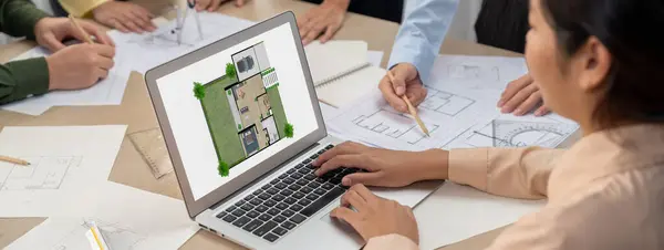 Professional architect decide the blueprint for eco-friendly house during discussion about changing blueprint plan at meeting table with architectural document scatter around. Closeup. Delineation