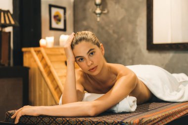 Beyaz havluyla beyaz kadın portresi kaplıca salonundaki rahat ve huzurlu sauna dolabının önündeki kaplıca yatağında yatıyor. Kapatın. Yan görüş. Huzur.