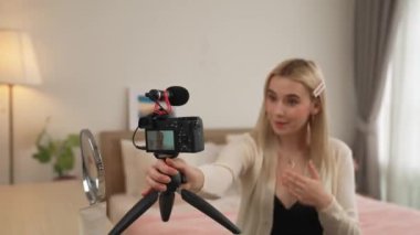 Sosyal medya için güzellik ve kozmetik video içeriği hazırlayan genç bir kadın. Seyirciye veya takipçiye nasıl sıvı ruj sürüleceğini gösterirken kamera ve ışık halkası kullanan bir güzellik blogcusu. Blithe