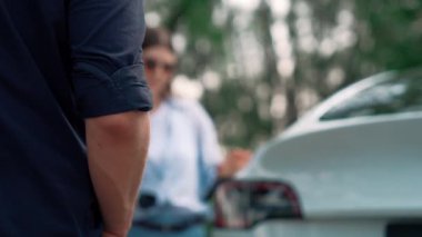 EV otomobili, tatilde milli park ve yeşillik ormanlarında çevre dostu elektrikli araçla seyahat eden çiftlerin bataryalarına elektrik yüklüyor. Yükselt