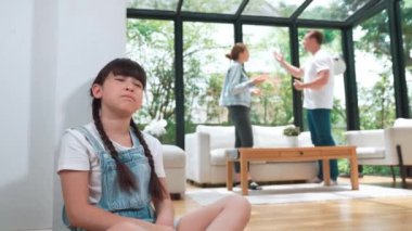 Stresli ve mutsuz genç kız köşeye kıvrılıp kulaklarını kapatarak arka planda ebeveyninin tartışmasını engelliyor. Evde aile içi şiddet ve travmatik çocukluk depresyona dönüşür. Titiz