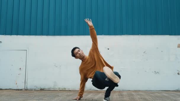 ヒスパニック系男性が壁の前で腕を伸ばし 踊るストリートダンス ヒップホップスタイルでボーイダンスを練習するカジュアルな衣装でダンサーや振付師のモーションショット アウトドアスポーツ 2024 ヒップホップ — ストック動画