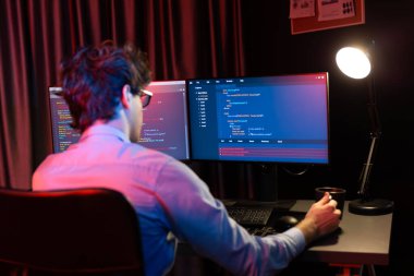 Uygulama pc ekranları ile çevrili çevrimiçi yazılım geliştirme bilgilerini yoğunlaştıran IT geliştiricisi, neon modern ofis evindeki web sitesinde yazılım için program yaratıyor. Toplayıcı.