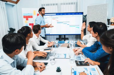 Proje yöneticisi monitörde proje yönetimi yazılım görüntülemesi, proje görevinin ilerlemesini izlemek ve toplantı masasında program planı yapmak suretiyle ekiple iletişim kurar ve işbirliği yapar. Tedbirli
