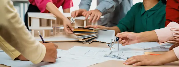 专业的建筑师团队选择可持续的建筑材料 而熟练的工程师则使用带有房屋模型和彩色调色板的分隔符蓝图放置在会议桌面上 穿上衣服页 — 图库照片