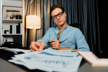 Akıllı iş adamının elinde evrak raporları var. Paragraf dinamik veritabanı, küresel hedef değerlendirme değeri kar şirketini analiz eden bilgisayar ekranına bakıyor. Bireysel.