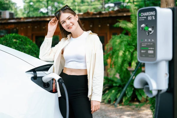 春の庭園 緑の都市の持続可能性と環境に優しいEvカーでEv電気自動車を充電する若い女性と持続可能な都市通勤 エクスペディエント — ストック写真