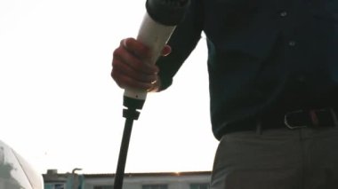 Genç adam, EV şarj aletini şehrin alışveriş merkezinin otoparkındaki şarj istasyonundan elektrik aküsünü şarj etmek için kullandı. Sürdürülebilir şehirde EV aracı tarafından şarj edilebilir enerji olarak kullanıldı.