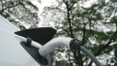 Green City Park 'taki otoparkta yavaş çekim EV elektrikli araba şarj bataryası. Sürdürülebilir ve çevre dostu şehir yolculuğu için yenilenebilir otomobil için alternatif temiz enerji teknolojisi. Yararlı