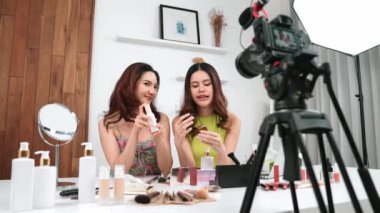İki kadın nüfuzlu partner sosyal medya veya blog için canlı yayın yapan video klip inceleme derisi çekiyorlar. Canlı kozmetik stüdyo ışığı olan genç bir kız çevrimiçi pazarlama kayıt oturumu yayını için.