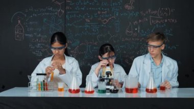 Öğrenci tahtada teoriyle deney yaparken güzel bir kız mikroskop altında araştırma yapıyor. Genç bilim adamı renkli çözeltiyi deneysel ekipmanlarla inceledi. Öğretim