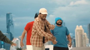 Profesyonel Asyalı sokak dansçısı çatıda çok kültürlü arkadaşlar dans ederken B boy dansı yapıyor. Genç modern dans grubu hip hop hareketi yapıyor. Tarz, moda, aksiyon. Açık hava sporu 2024 hiphop..