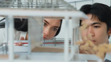 Ev modeli yapısını ölçmek için birlikte çalışan kooperatif mühendisi kapatın. Genç ve güzel mimar ev modelini ölçerken erkek mühendis performansını destekliyor. Tertemiz..