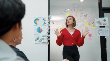 Yetenekli genç ve güzel iş kadını, yaratıcı iş toplantısında yakışıklı yönetici dinlerken zihin haritalama ve istatistiksel grafik kullanarak pazarlama fikrini kendine güvenle sunuyor. Tertemiz..