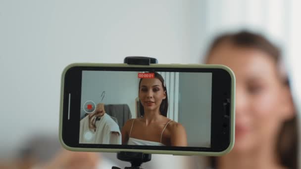 若いソーシャルメディアコンテンツクリエイターの女性がファッションビデオを作ります ブロガーは 説得力のあるオンライン衣料品をオーディエンスやフォロワーに販売しながら セルフィースティックとライトリングを使用してカメラに笑顔 アディット — ストック動画