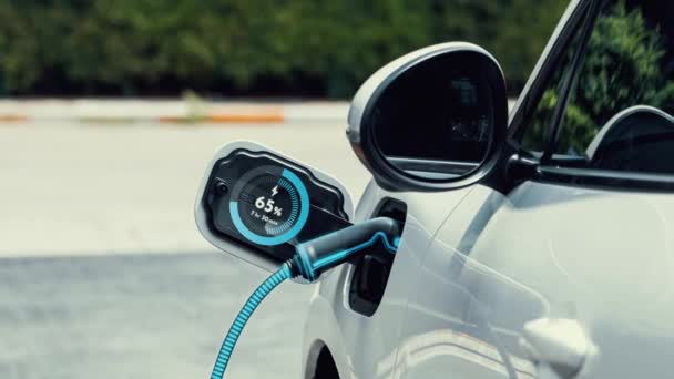 充電ステーションの将来の駐車場でのEv充電器を使用した電気自動車の充電は 代替および持続可能なエネルギーを使用して充電式Ev車のバッテリーステータスホログラムを表示します — ストック動画