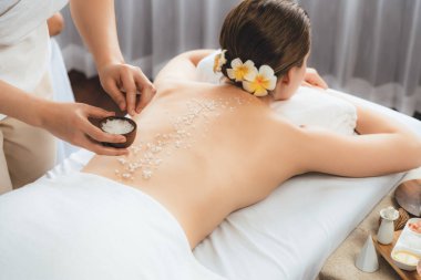 Lüks spa salonlarında sıcak mum ışığında cilt bakımı yaptıran kadın müşteri. Sağlık Spa vücut fırçasında tuz temizleme güzellik tedavisi. Sessiz.