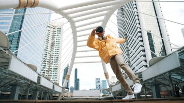 Asyalı hippi break dans çalışmasının düşük açılı kamerası ya da kulaklık takarken break dans performansı. Serbest dans, break dans, sokak dansı. Neşeli bir ruh hali. Açık hava sporu 2024. Yumuşak bir şekilde..