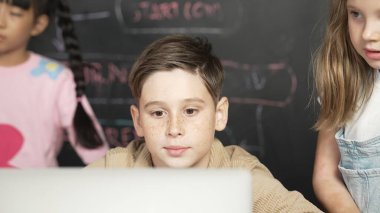 Çocuğun dizüstü bilgisayar mühendisliği kodunu ve yazım programını kullanırken STEM teknoloji sınıfında kontrol sahibi olan çeşitli çocuklardan oluşan bir grubun hemen karatahtayla yazılmış hali. Etkinlik.