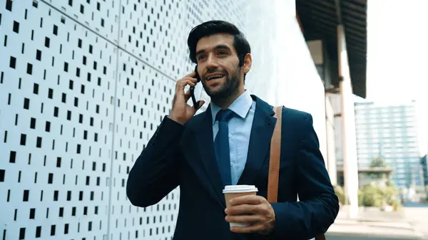Smart business man using phone to talking about business investment. Happy manager walking at street while talking on smart phone to discuss business plan or marketing strategy or working. Exultant.