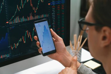 Akıllı borsa yatırımcıları ekranda akıllı telefon ile piyasa borsasını işaret ederek dizüstü bilgisayarın yanı sıra en yüksek dinamik yatırım oranını göstererek, modern işyerindeki veri planlamasına odaklanıyorlar. Bireysel.