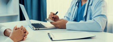 Klinikteki ya da hastane ofisindeki doktor randevusuna katılan hasta, tıbbi tedavi seçeneklerini tartışıyor ve muayene sonuçlarını ya da hastalıkla ilgili tıbbi kayıtları açıklıyor. Panorama Katı