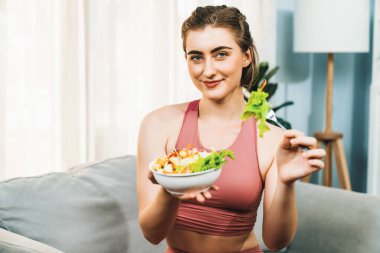 Spor giyimli sağlıklı ve vejetaryen bir kadın bir kase meyve ve sebzeyle. Sağlıklı beslenme ve spor için vejetaryen yaşam tarzı ev konseptinde vücut fiziği.
