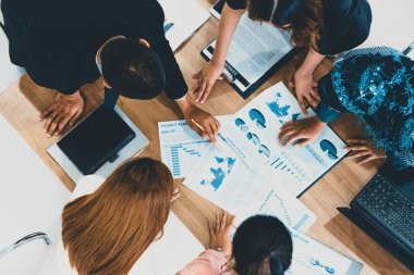 Modern ofisteki iş adamları ve iş kadınlarıyla grup toplantısındaki iş adamlarının en üst düzey görüşü, masada dizüstü bilgisayar, kahve ve belge ile. Kurumsal şirketler uds