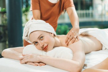 Bir çift güzel genç kadın sırt masajı sırasında beyaz spa yatağında yatıyor. Çekici beyaz kadın geleneksel spa odasında sırt masajı yaptırıyor. Rahatlatıcı ve sağlıklı konsept Huzur.