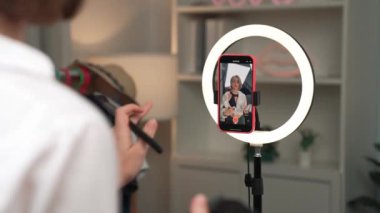 Arka plan etkileyicisi, vlog video gözden geçirme makyaj primi sosyal medya ya da blog kullanarak akıllı telefon yayınıyla canlı çekim yapıyor. İnternetteki pazarlama kaydı için kozmetik stüdyosu ışıklandırması olan kız.